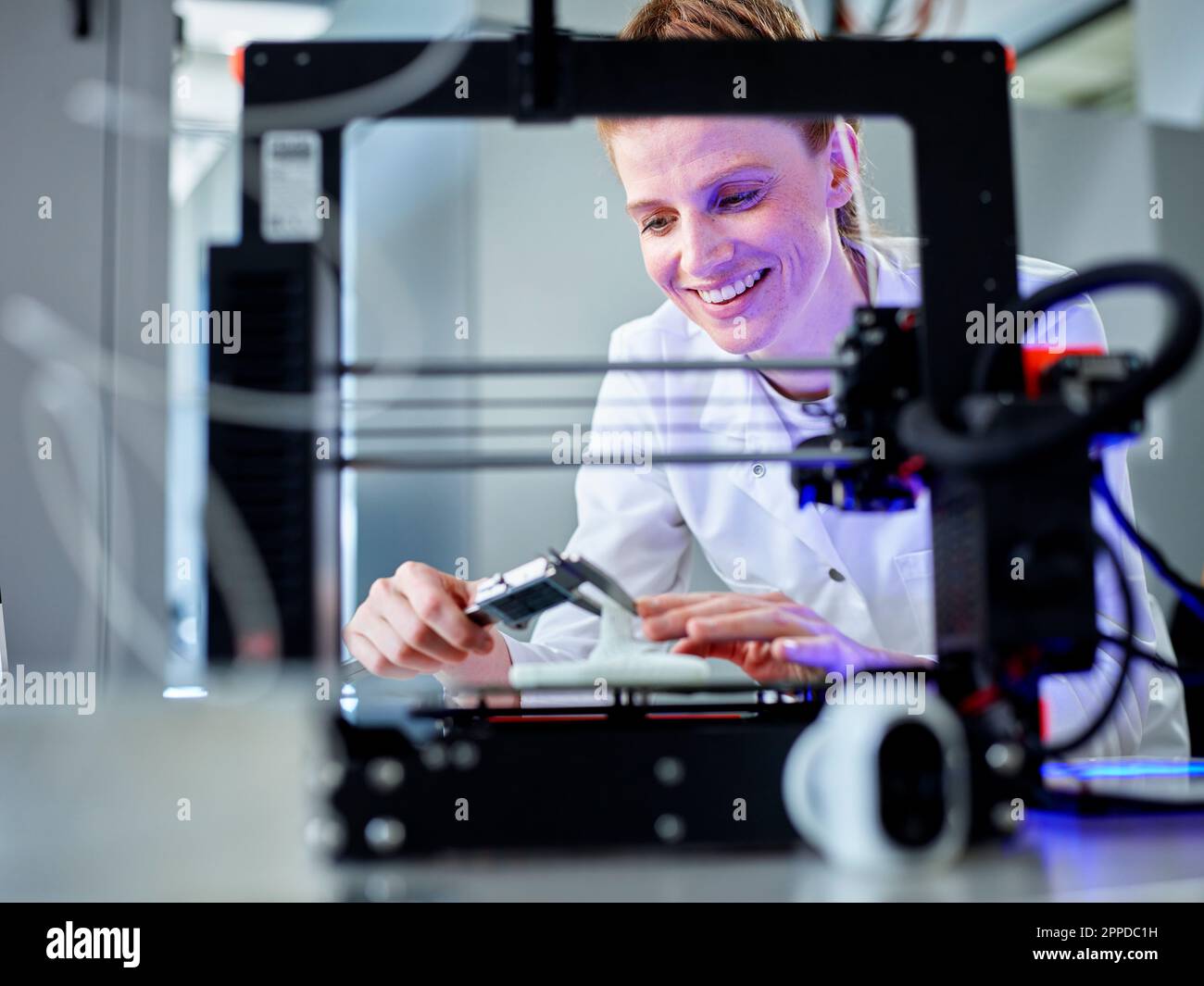 Happy engineer operating 3D printing machine in laboratory Stock Photo