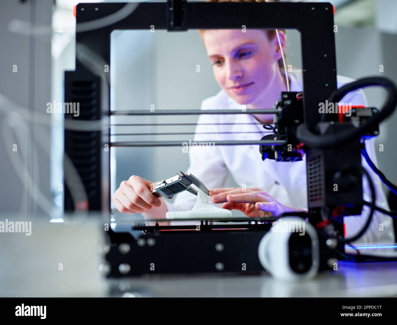 Engineer using vernier calliper operating on 3D printing machine Stock Photo