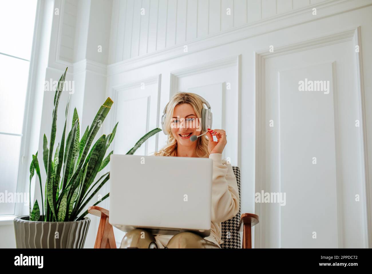 Smiling freelancer wearing headset using laptop at home Stock Photo