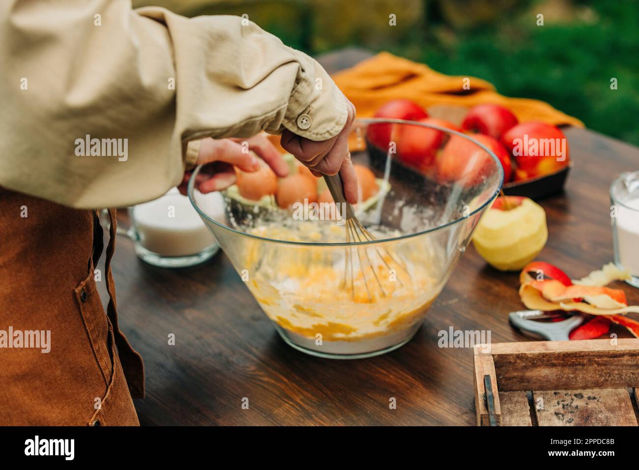 Woman whipping eggs in mixing bowl at garden table Stock Photo
