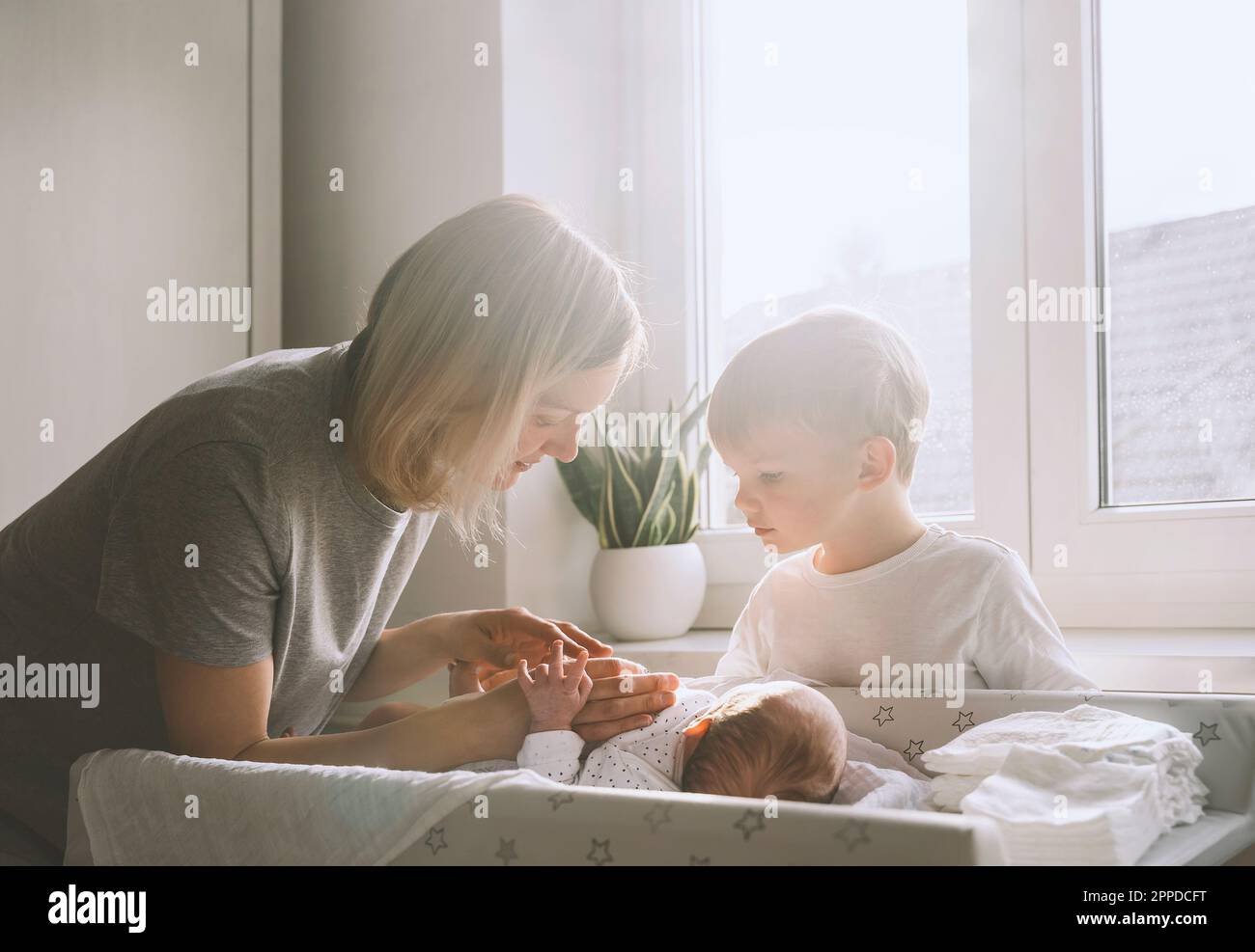 Mother and boy taking care of baby boy at home Stock Photo