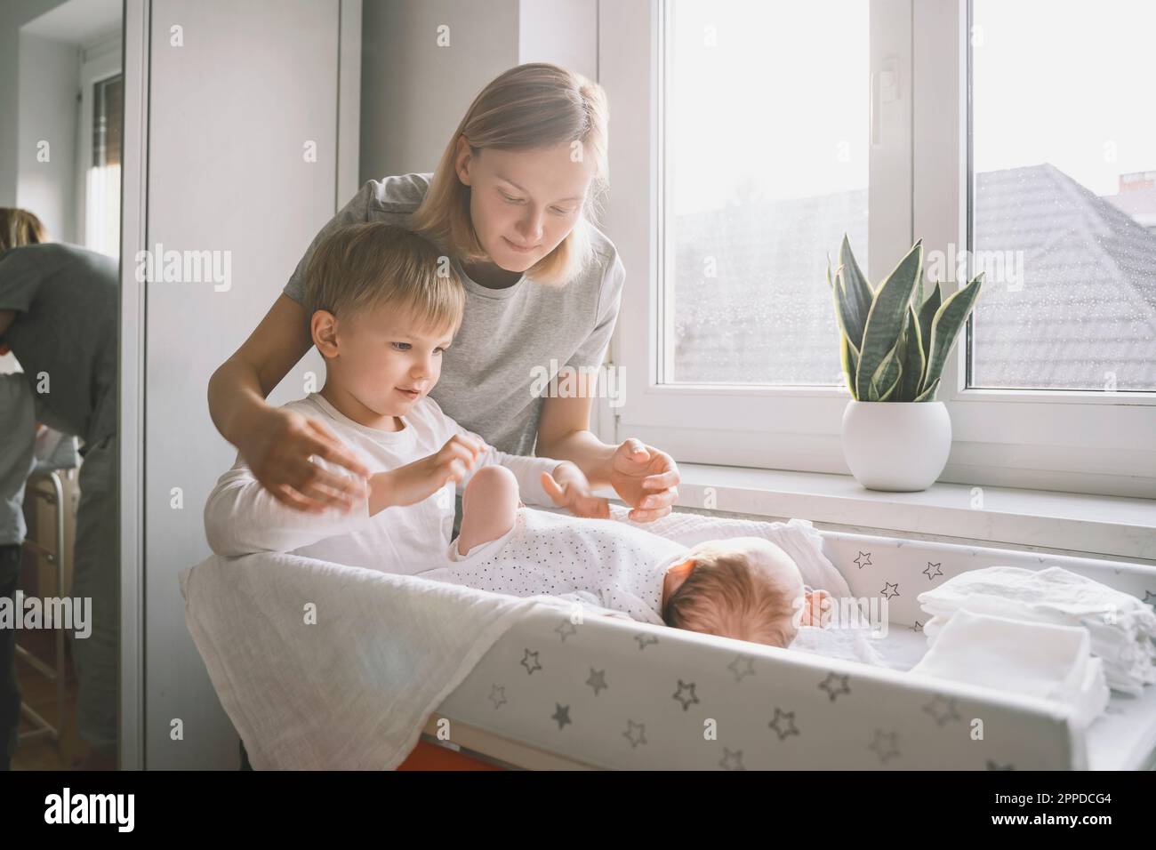 Woman and boy looking after baby sleeping on changing table at home