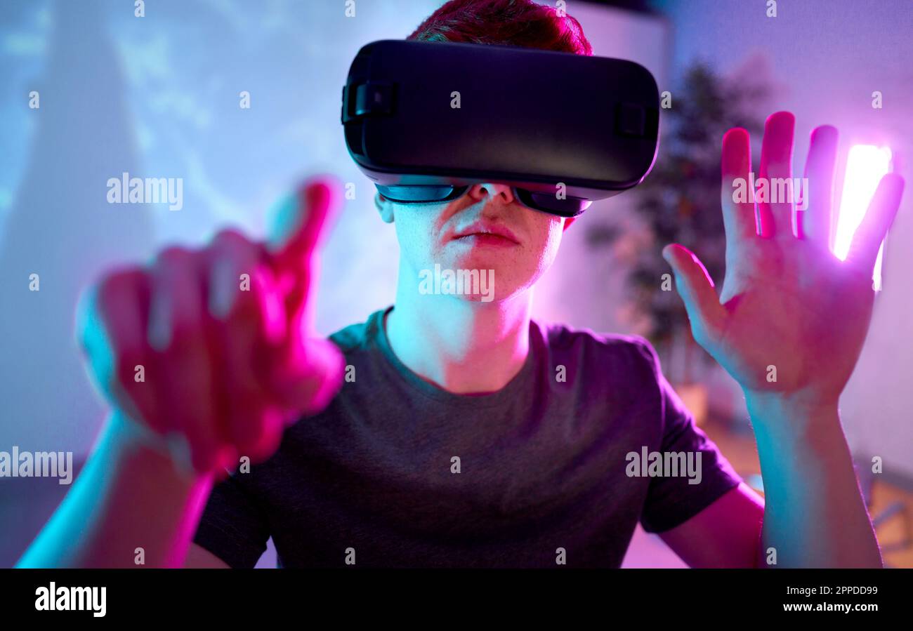 Young man wearing VR glasses gesturing at home Stock Photo