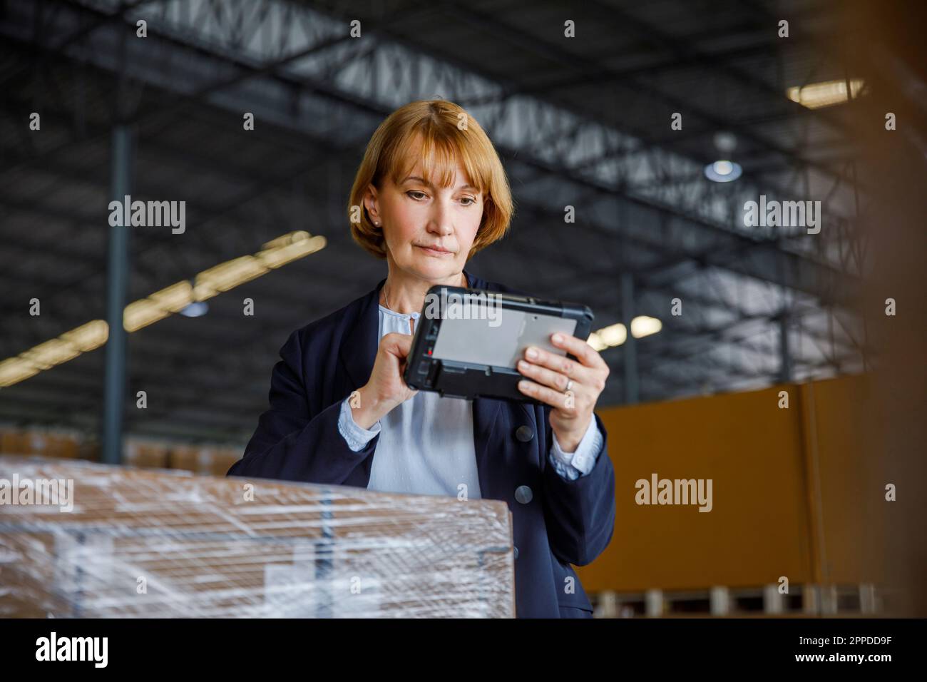 Manager using tablet PC standing by stocks in warehouse Stock Photo