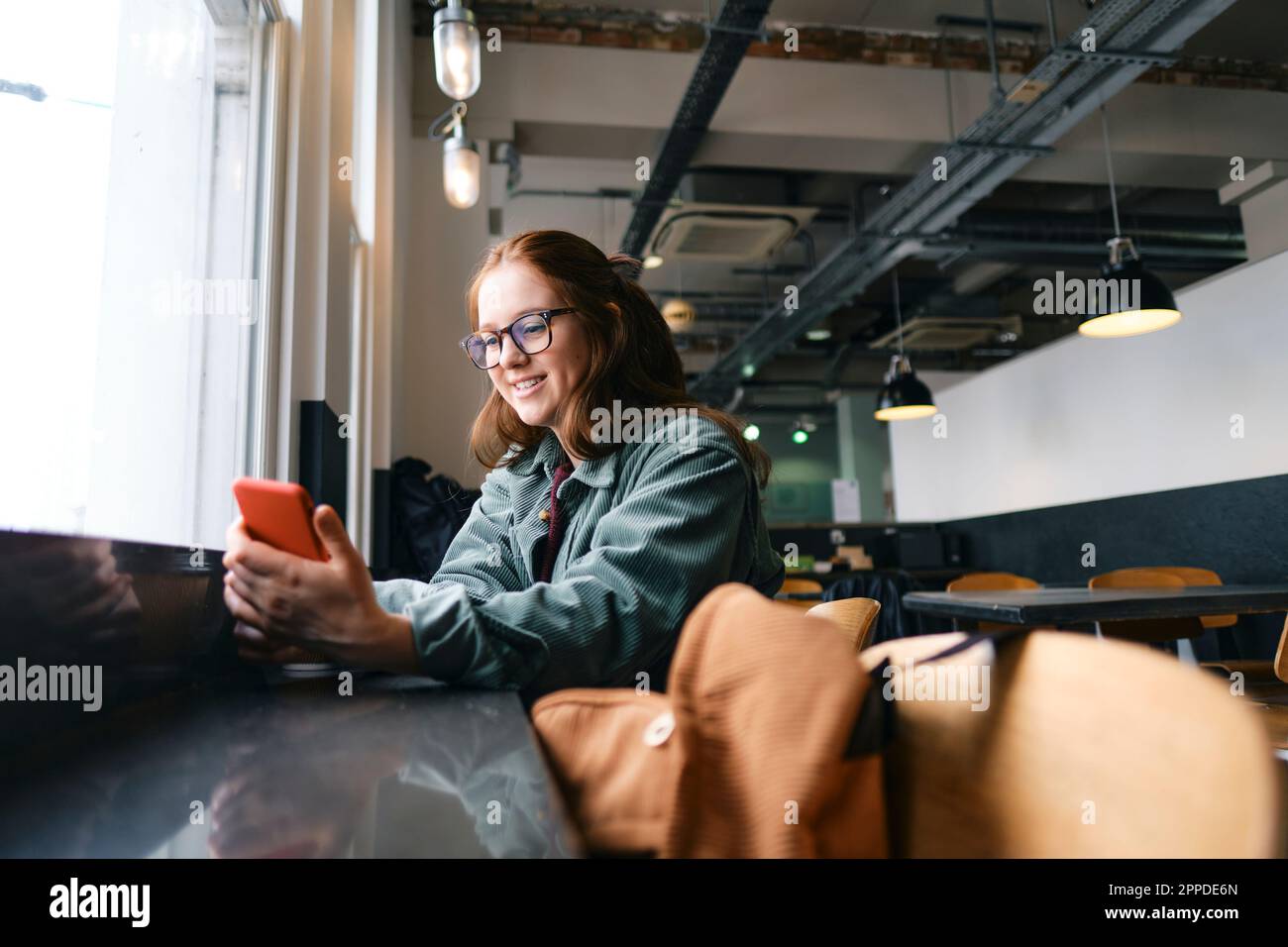 Smiling young freelancer using mobile phone in cafe Stock Photo
