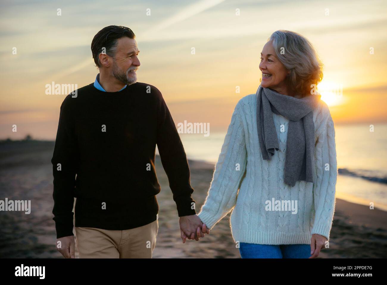 happy mature couple holding hands and walking at beach Stock Photo - Alamy