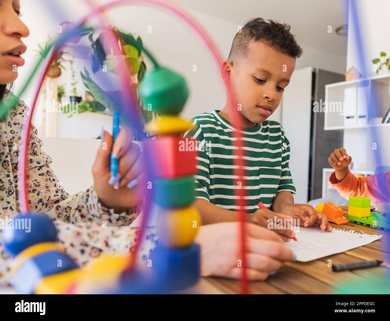 Mother helping boy in painting at home Stock Photo
