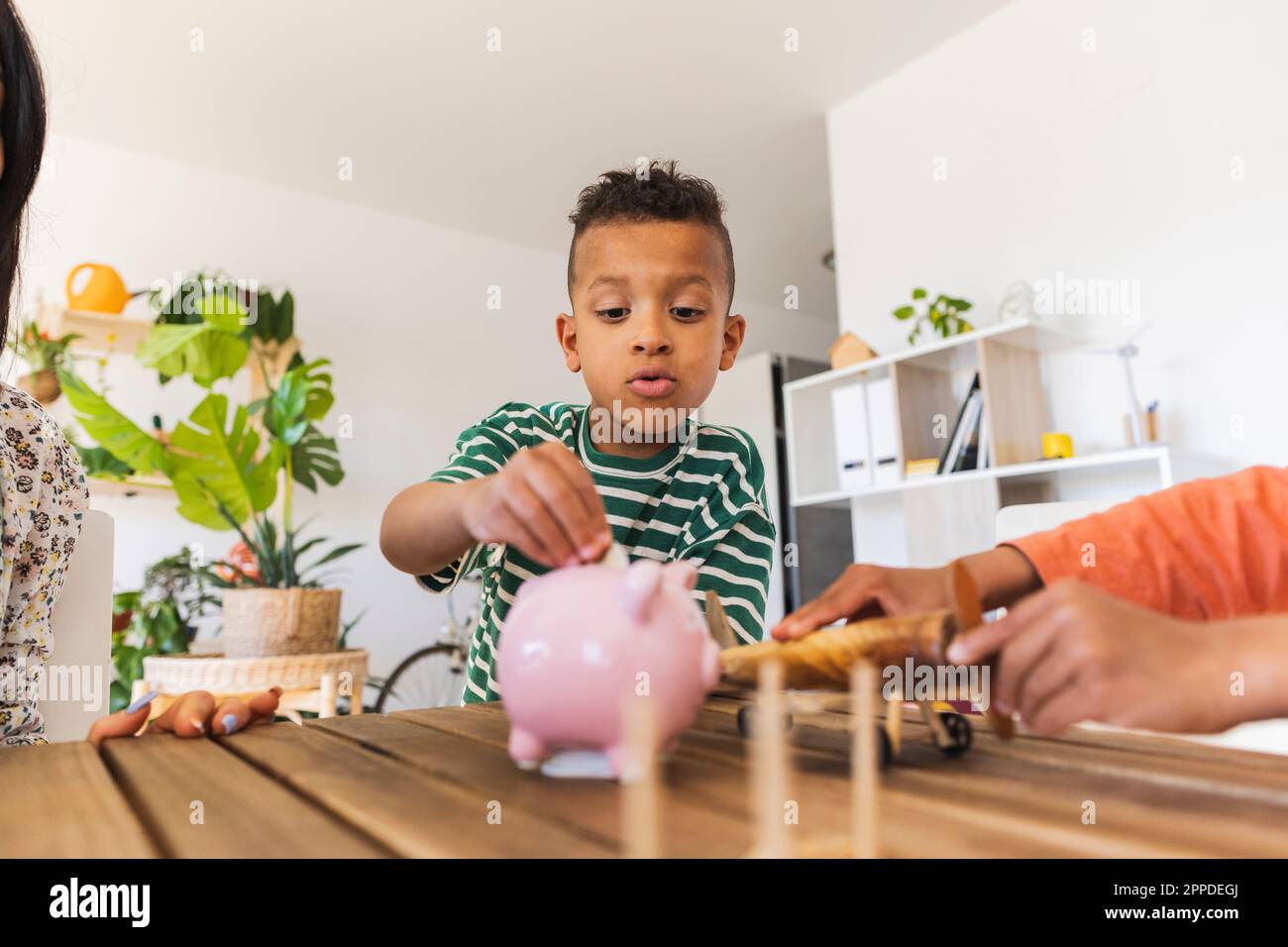 Boy inserting coin into piggy bank at home Stock Photo - Alamy