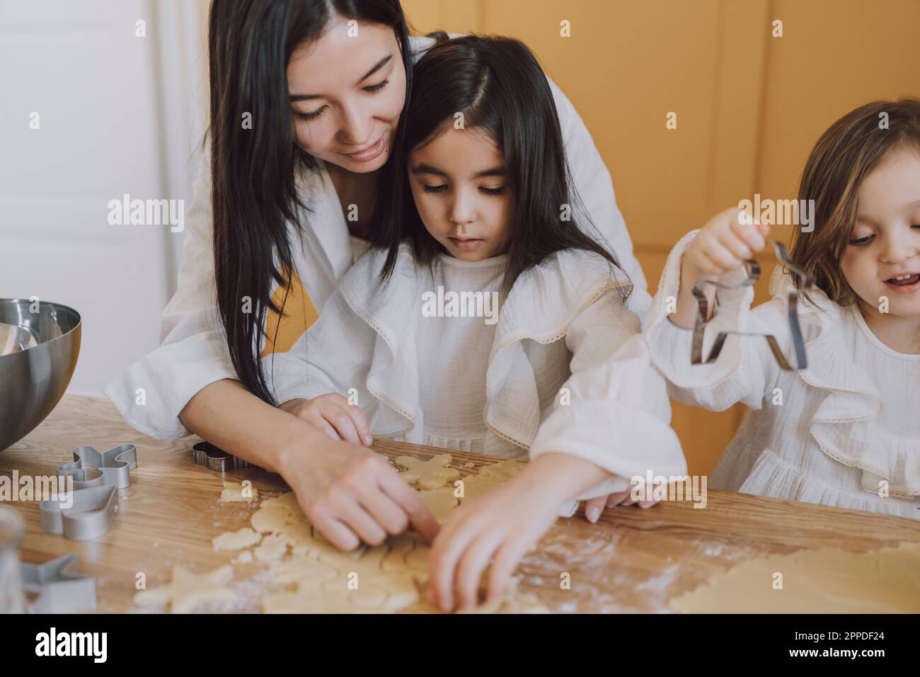 Mother helping daughters in making cookies for Easter Stock Photo