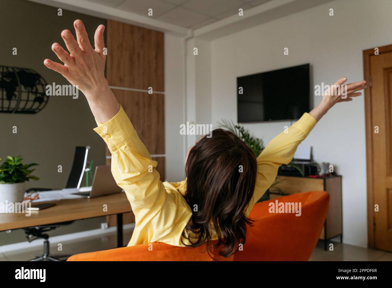 Real estate agent with arms raised sitting on chair Stock Photo Alamy