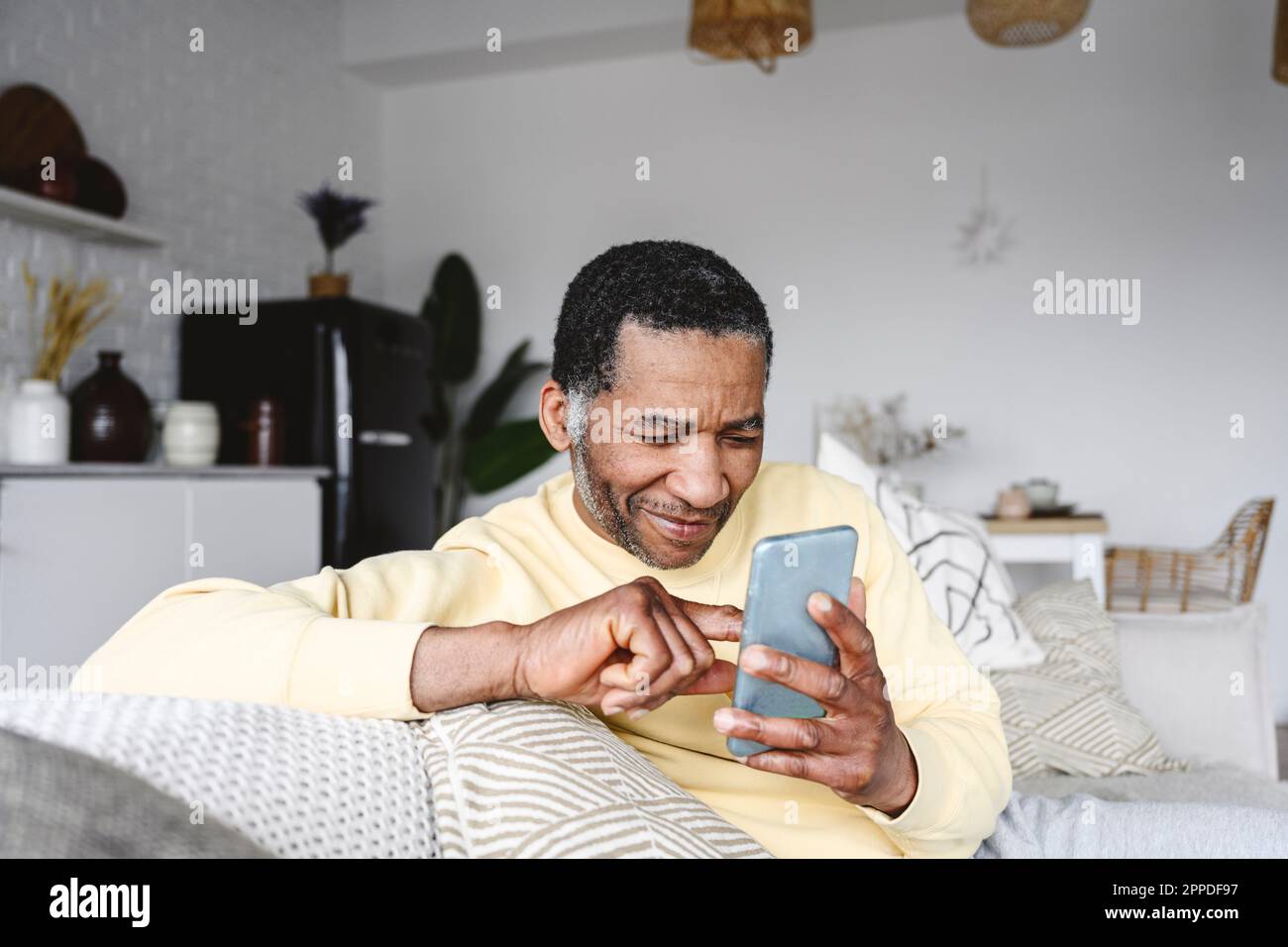 Smiling mature man using smart phone at home Stock Photo