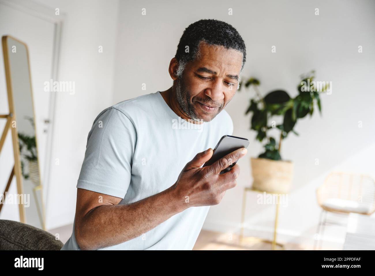 Mature man using mobile phone at home Stock Photo