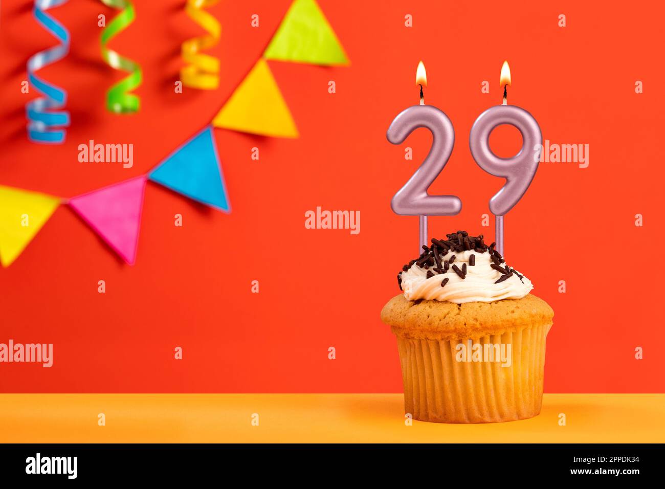 Number 29 Candle - Birthday cake on orange background with bunting Stock Photo
