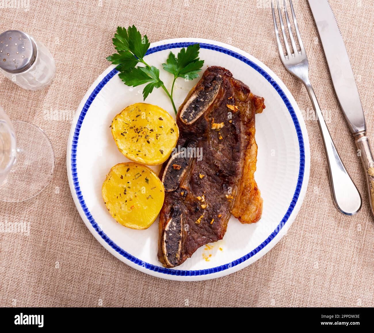 Spanish cuisine churrasco de ternera, spare ribs with potatoes on ceramic  plate Stock Photo - Alamy