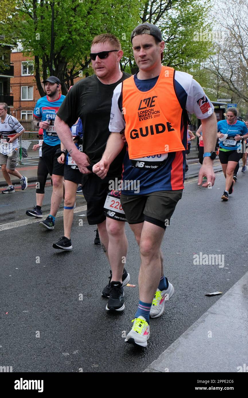 London, UK. 23rd April, 2023. A visually impaired runner is assisted by a guide as they proceed along Jamaica Road - the 11th mile of the 26.2 mile-long route. The London Marathon returns to its original scheduling in spring having being moved to autumn during the Covid pandemic, with 47,000 runners taking to the streets.  Credit: Eleventh Hour Photography/Alamy Live News Stock Photo