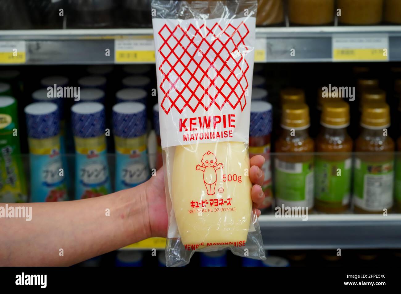 Tokyo, Japan - April 15, 2023 : Close up of Japanese style Kewpie brand mayonnaise held in hand in a local supermarket aisle with product labels Stock Photo