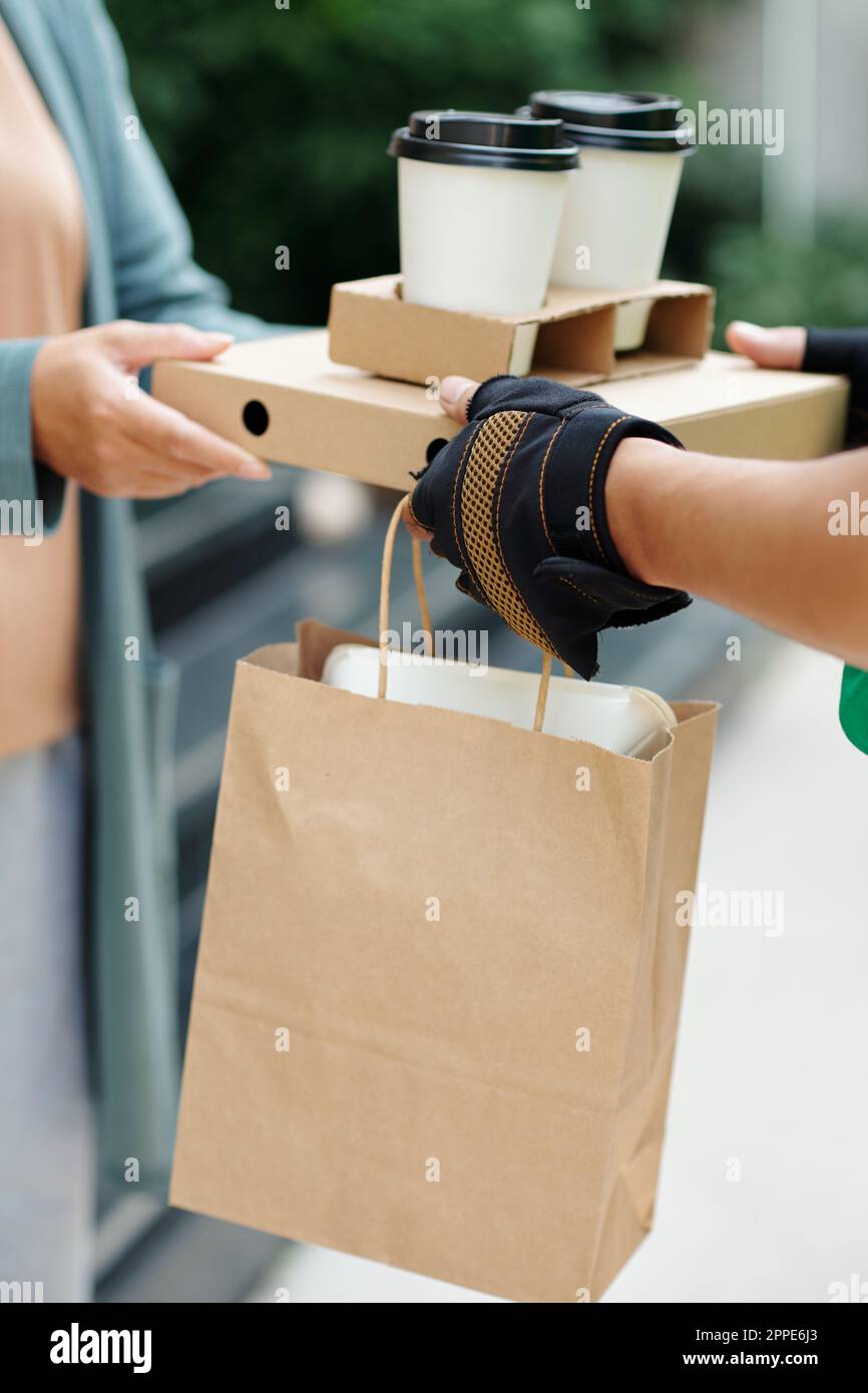 Restaurant courier giving order to customer, lunch delivery Stock Photo
