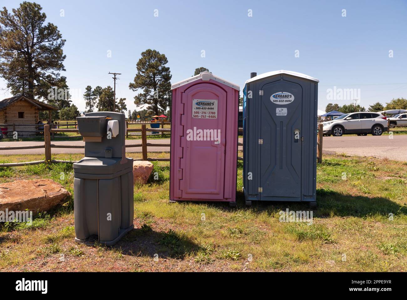 Two outdoor portable toilets, a pink one for women, and an outdoor hand washing station at an outdoor festival. Stock Photo