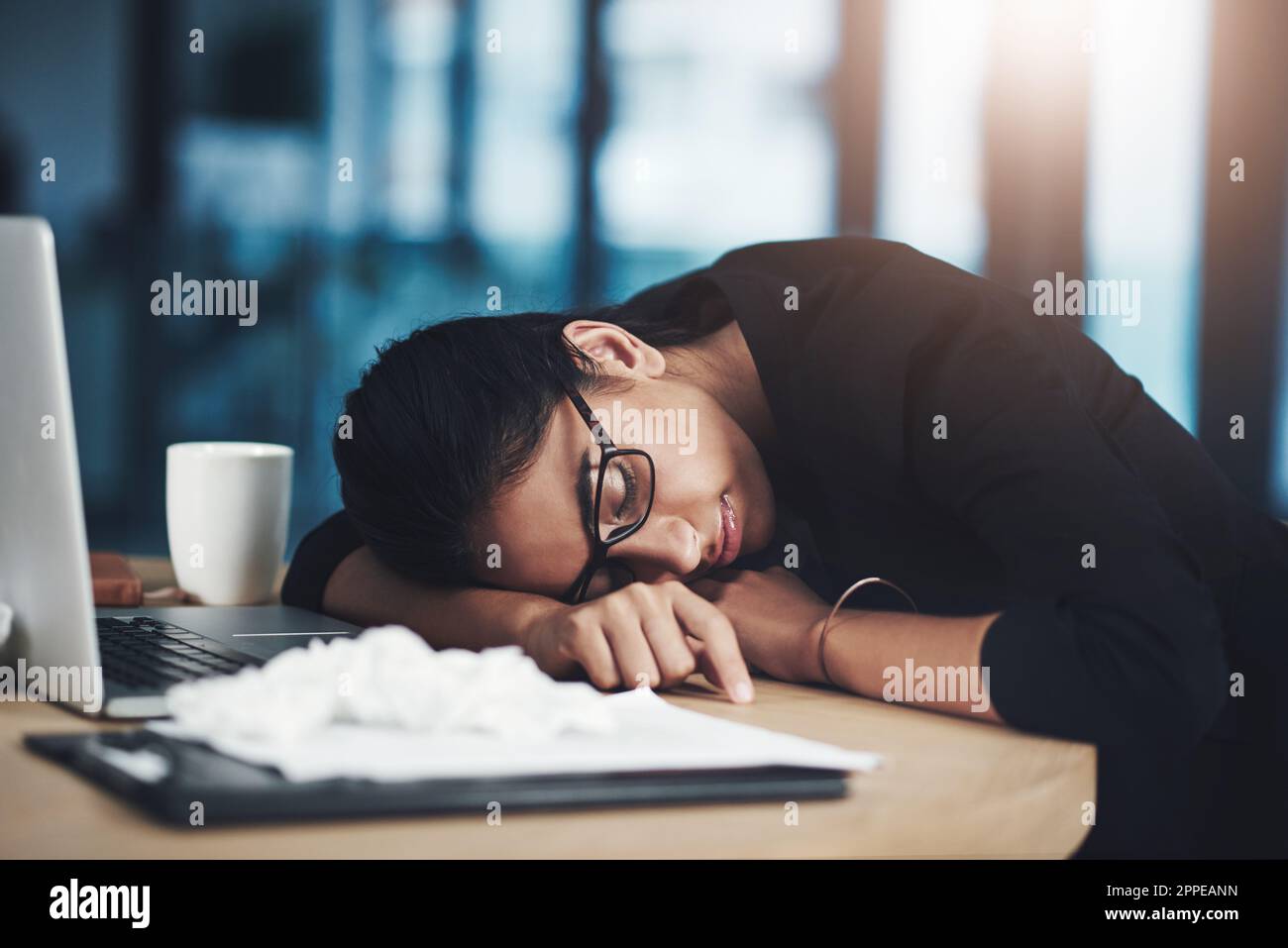 Catching some zzzs. a young businesswoman sleeping at her desk while ...