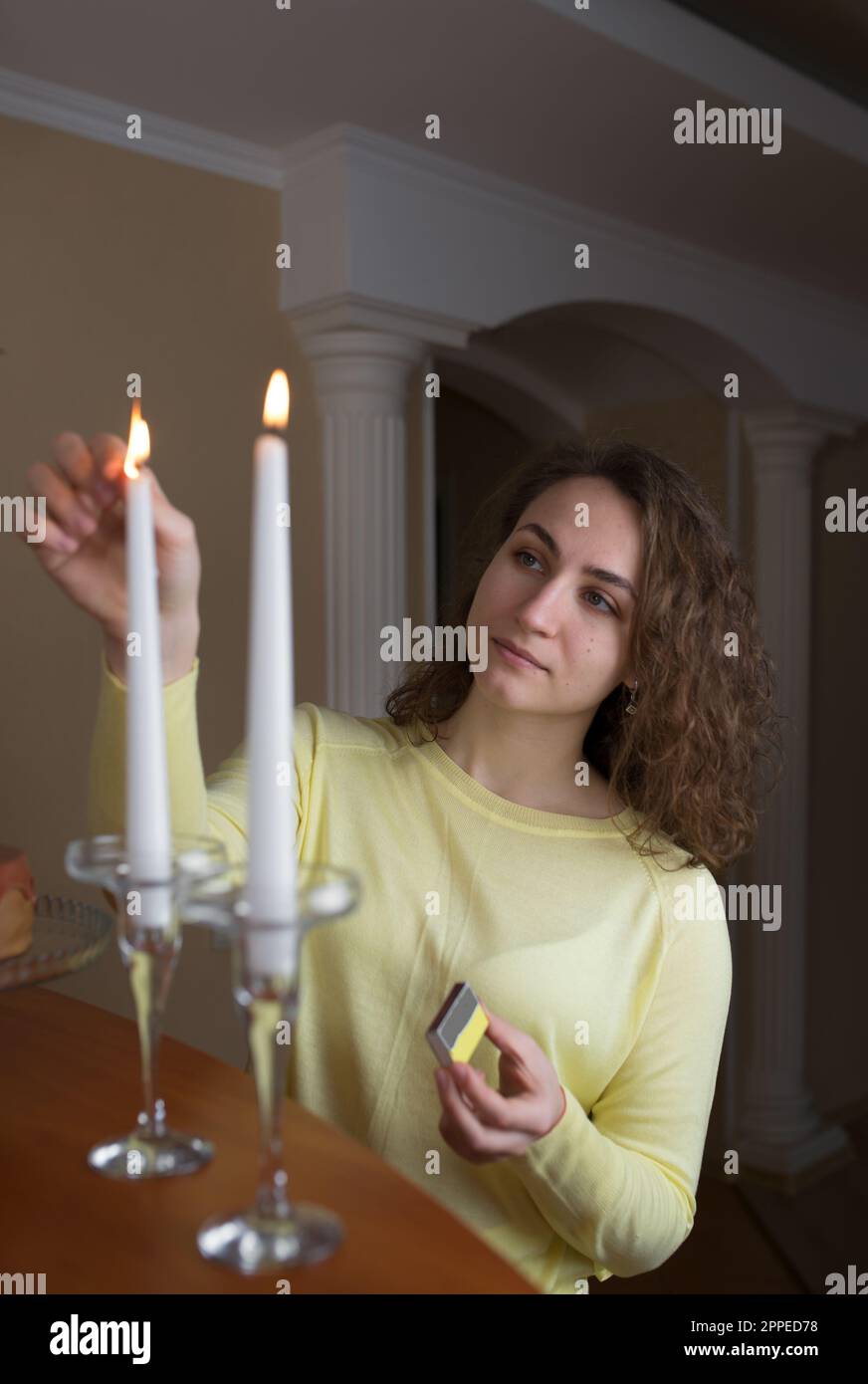 young girl with long hair lights candles in the kitchen at home Stock Photo Alamy