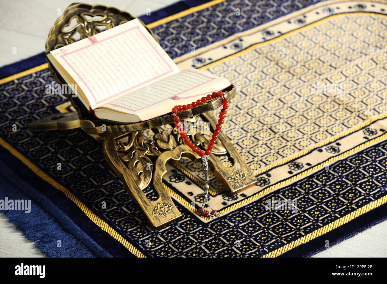 Rehal with open Quran and Misbaha on Muslim prayer rug, space for text ...