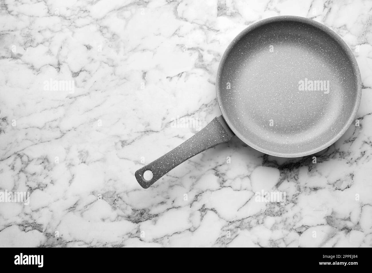 New non-stick frying pan on white marble table, top view. Space for text Stock Photo