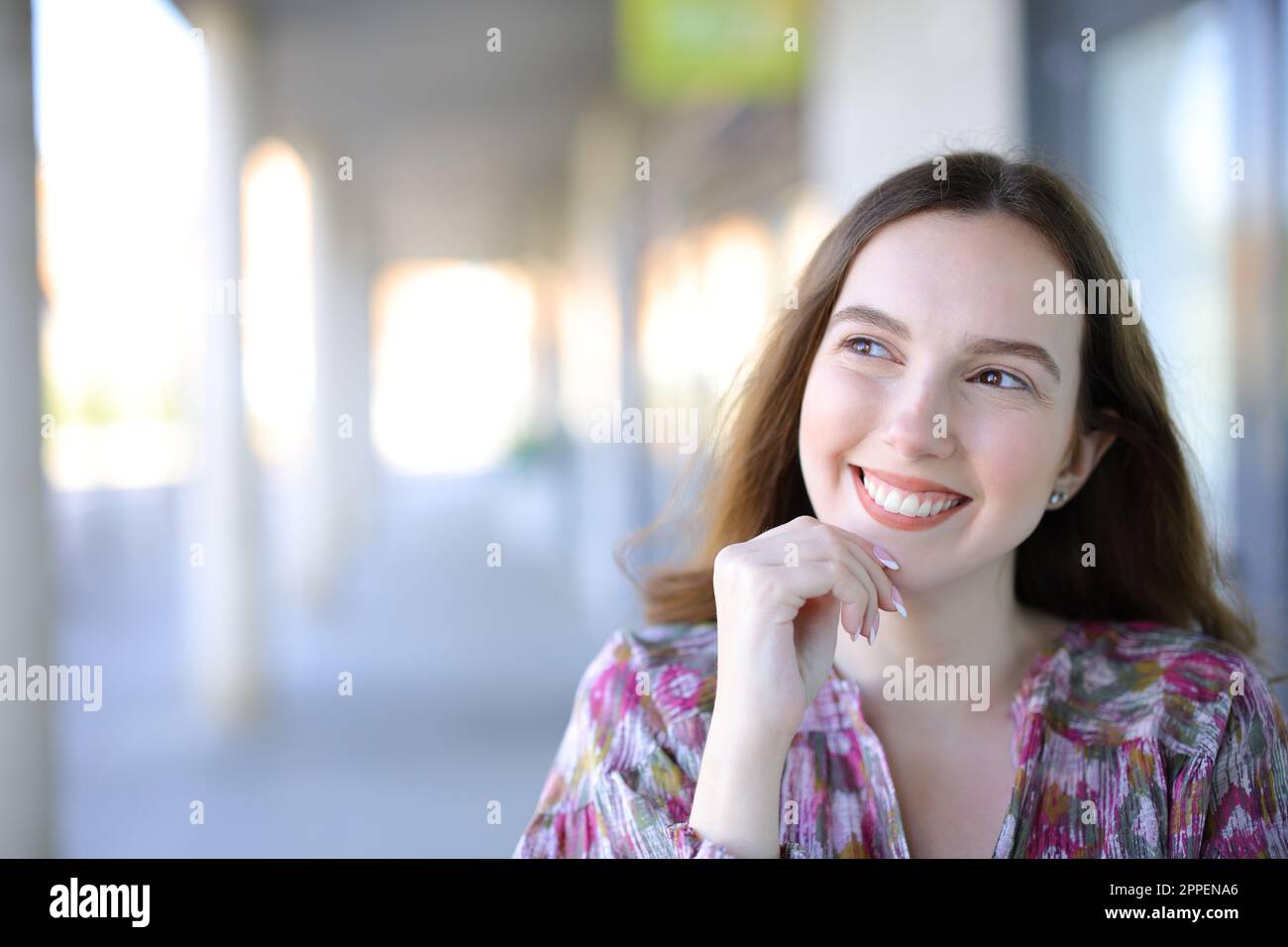 Happy woman thinking looking sideways in the street Stock Photo