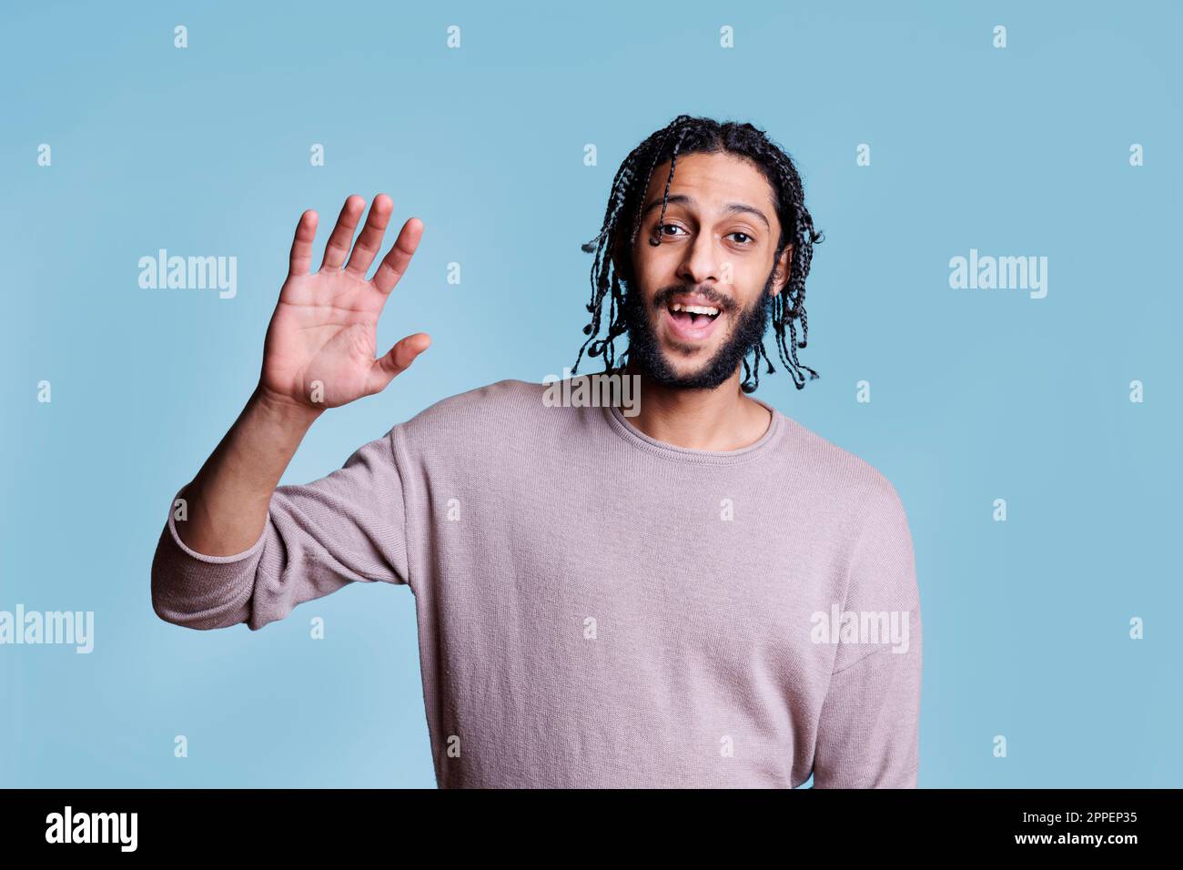 Smiling attractive arab man waving hi with hand with cheerful facial
