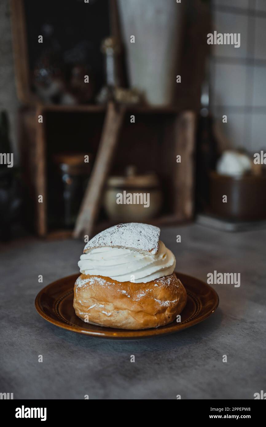 Bun with whipped cream on plate Stock Photo