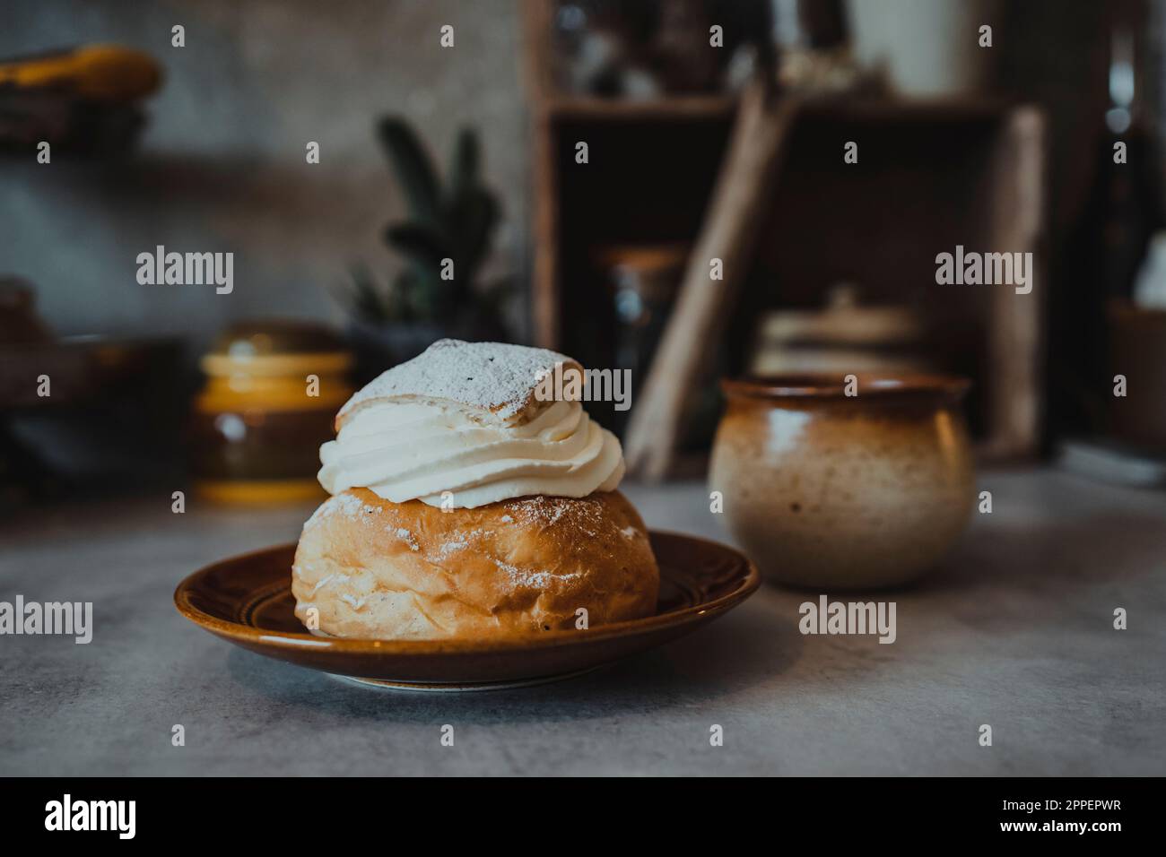 Bun with whipped cream on plate Stock Photo