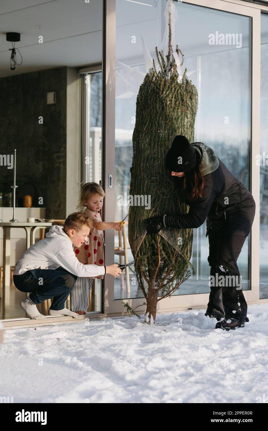 Woman with children preparing Christmas tree in front of house Stock Photo