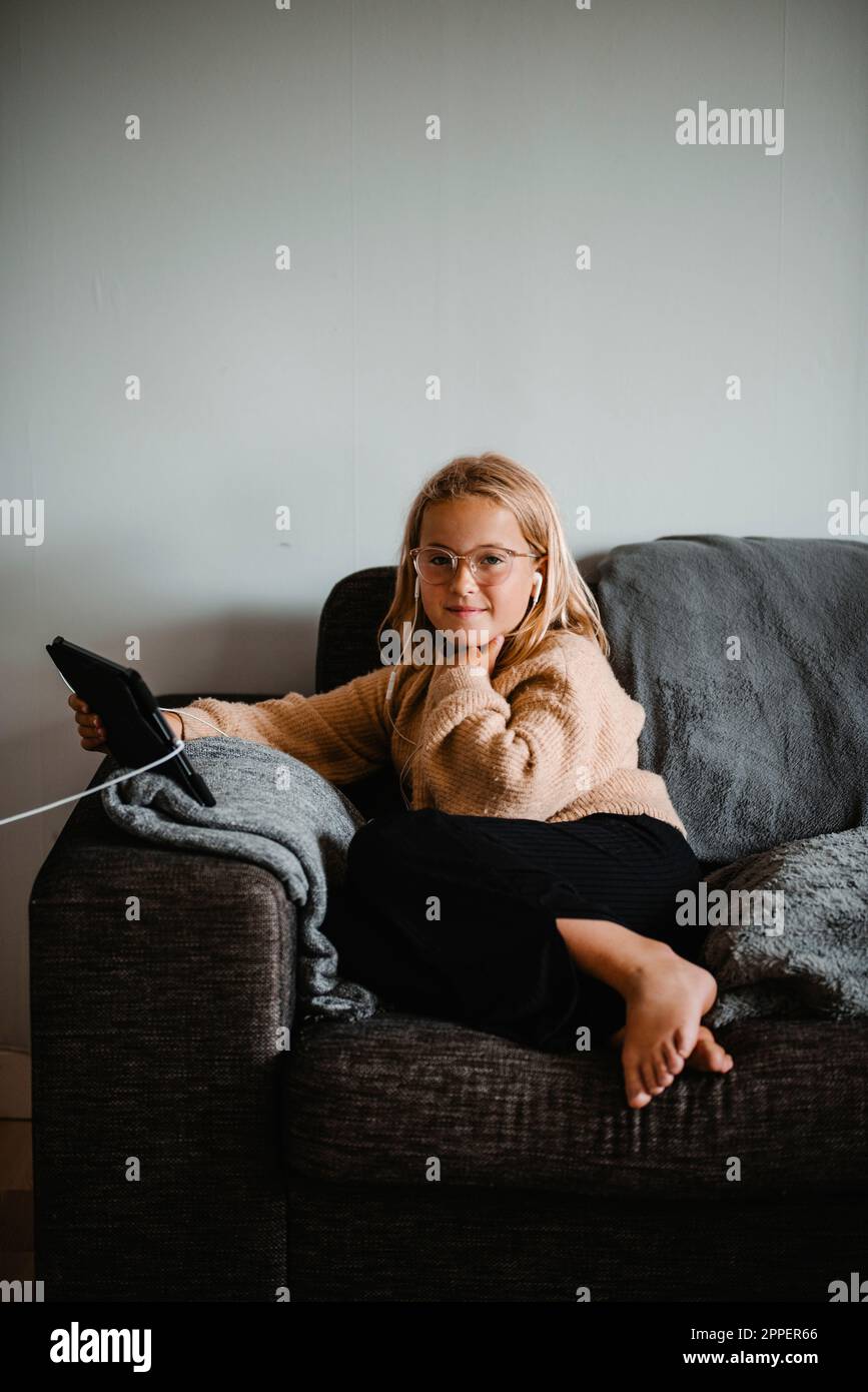 Girl on sofa using digital tablet Stock Photo