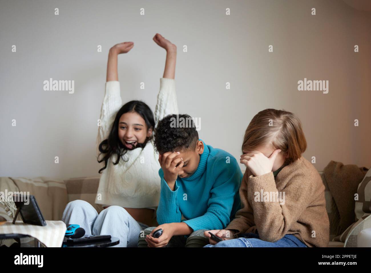 Children playing video games at home and celebrating Stock Photo