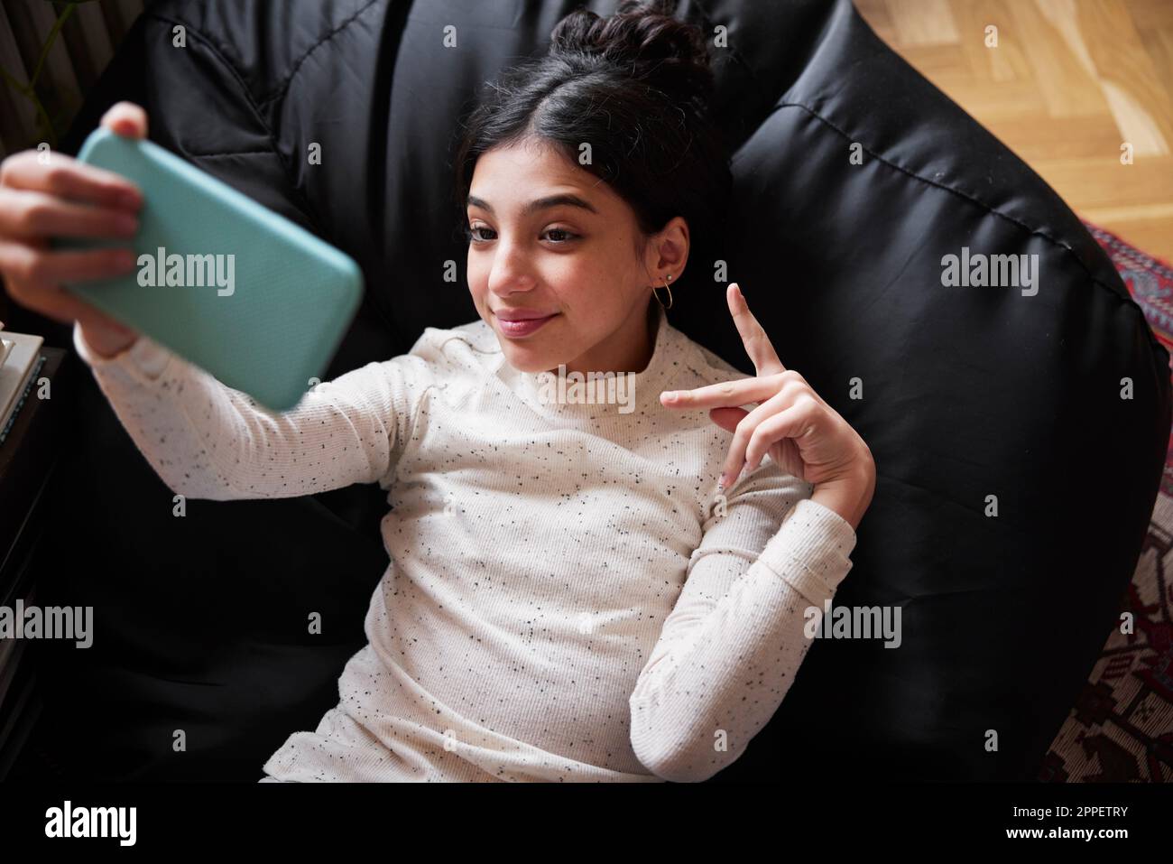 Girl lying on bean bag and taking selfie Stock Photo - Alamy