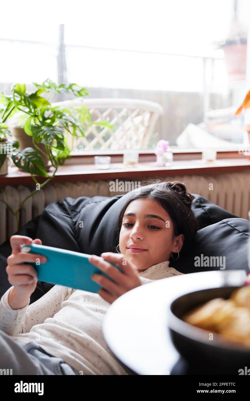 Girl lying on bean bag and playing video games Stock Photo