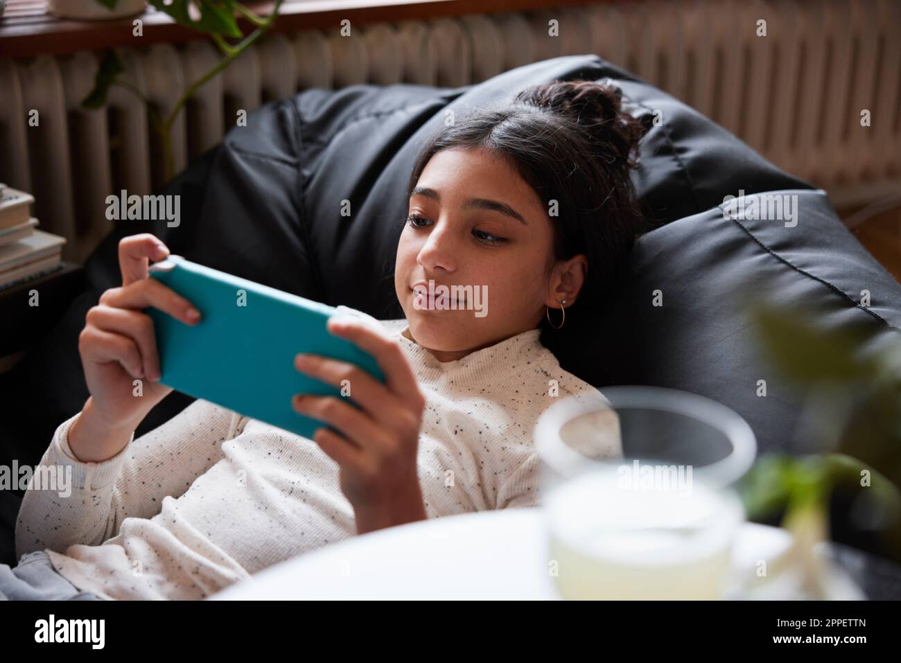 Girl lying on bean bag and playing video games Stock Photo