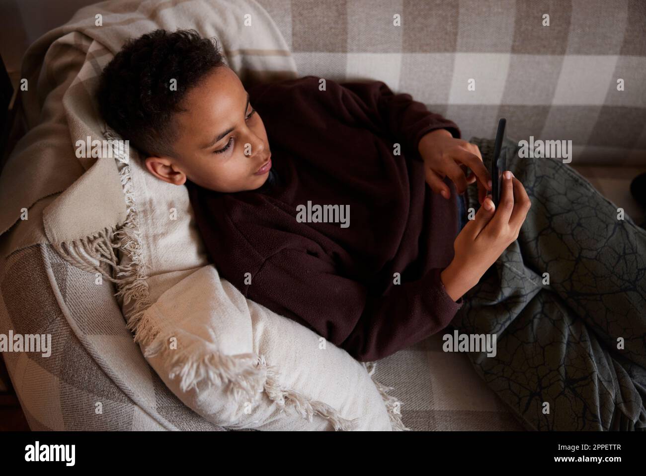 Boy lying on sofa and using phone Stock Photo