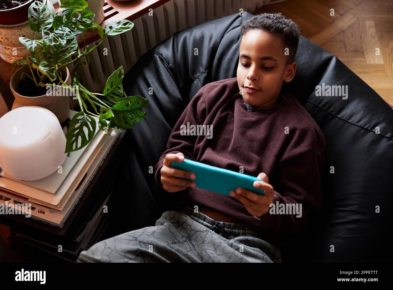 Boy lying on bean bag and playing video games Stock Photo - Alamy