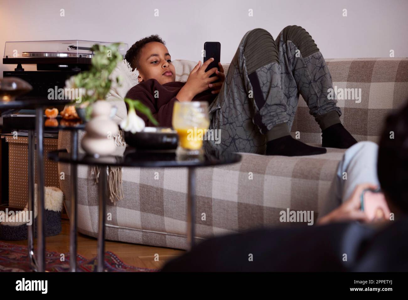 Boy lying on sofa and using phone Stock Photo