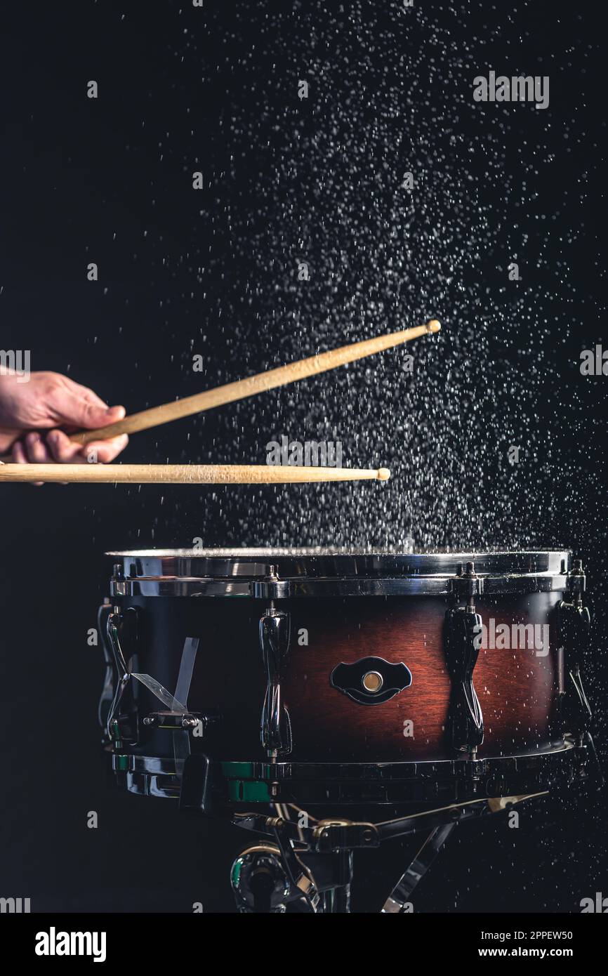 Drummer using drum sticks hitting snare drum with splashing water Stock
