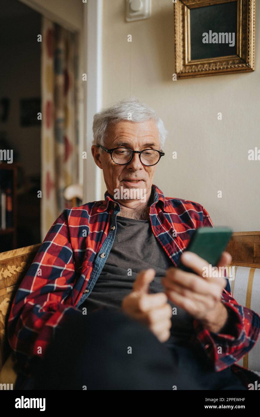 Senior man using smart phone at home Stock Photo