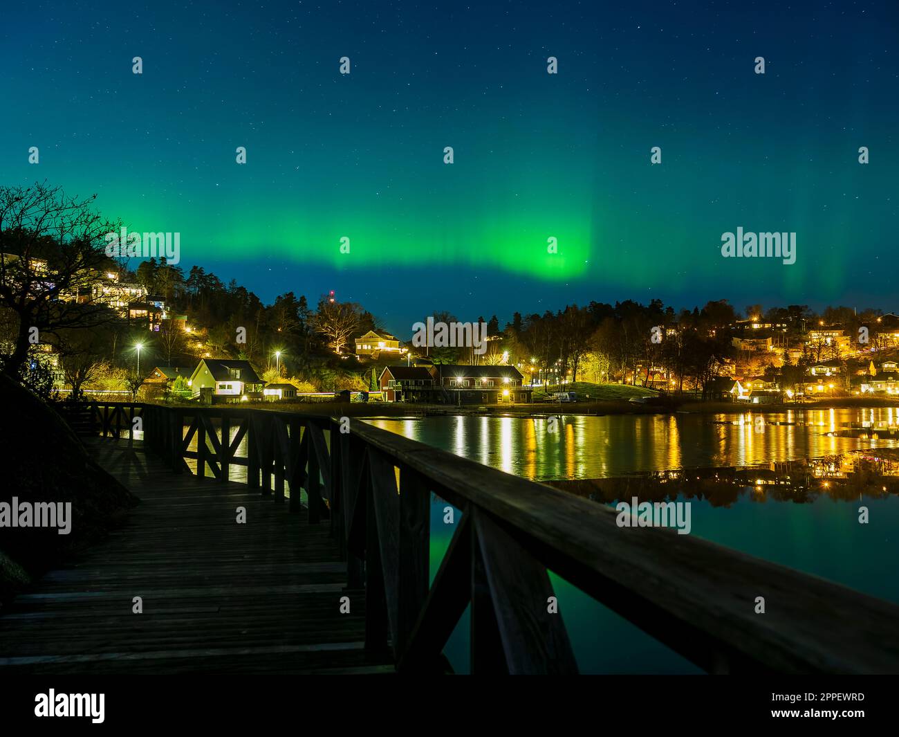 Northern lights over village on coast Stock Photo