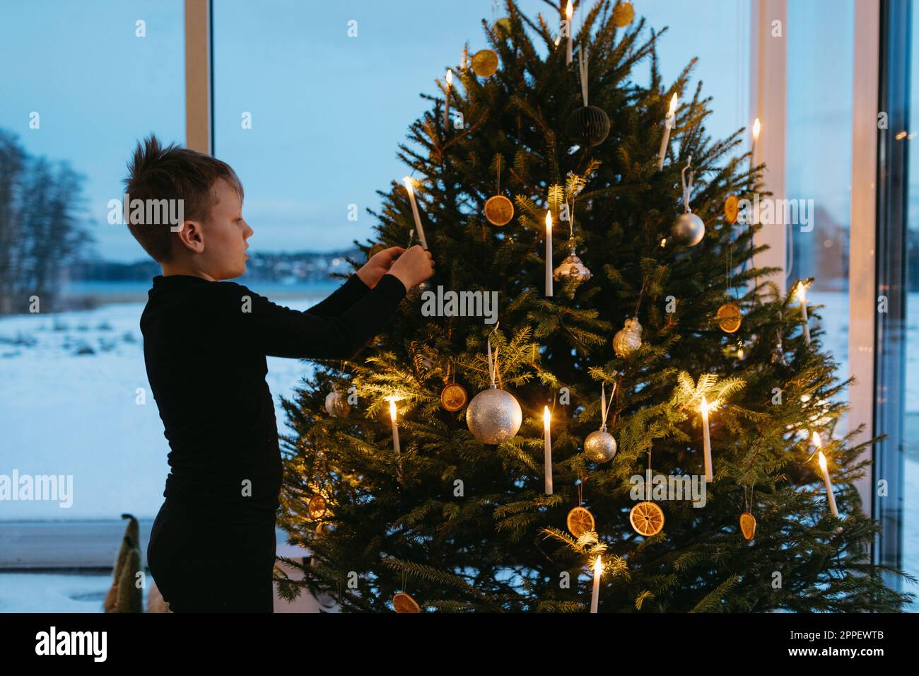 https://c8.alamy.com/comp/2PPEWTB/boy-decorating-christmas-tree-at-home-2PPEWTB.jpg