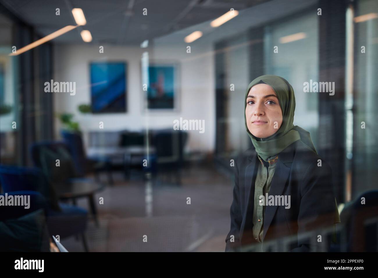Woman in headscarf looking through window Stock Photo