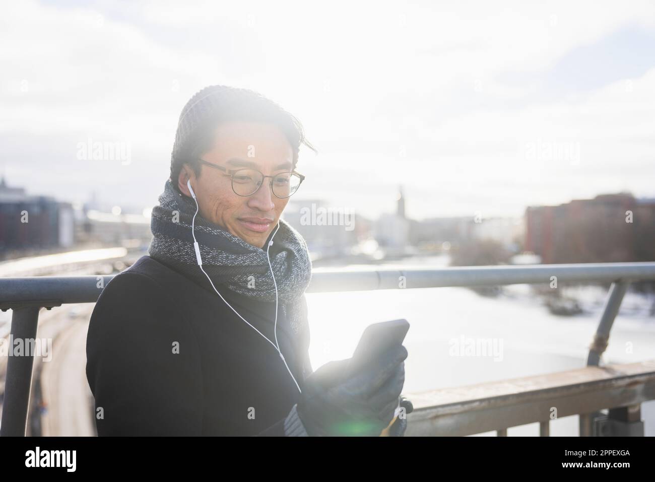 Handsome man with smartphone on footbridge Stock Photo