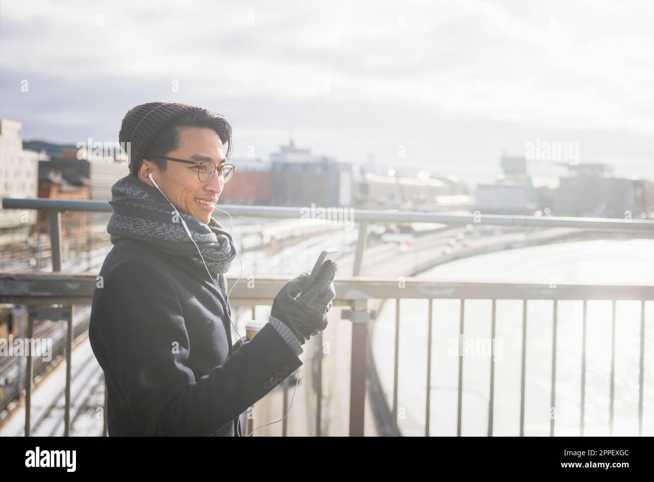 Handsome man with smartphone on footbridge Stock Photo