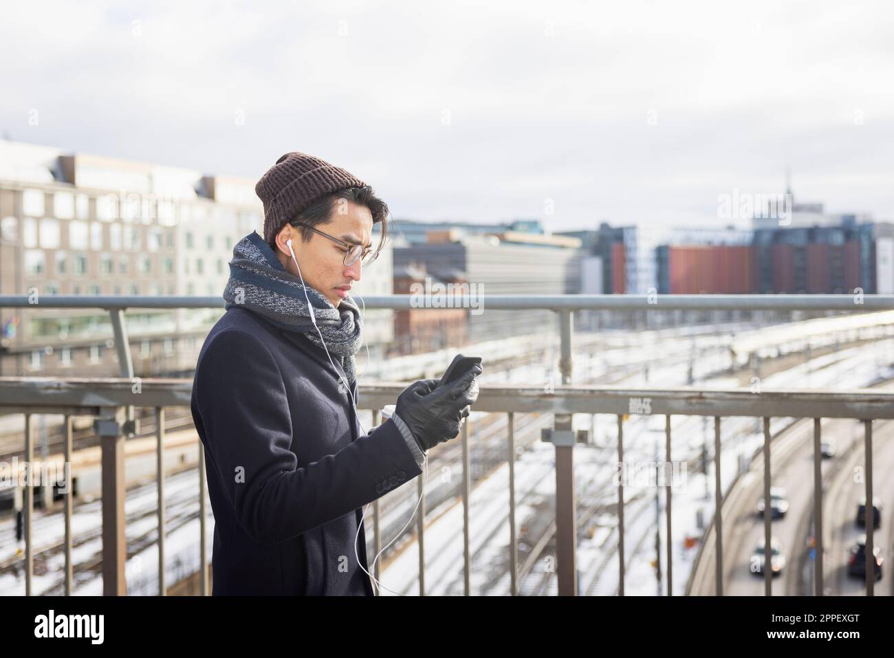 Handsome man with smartphone on footbridge Stock Photo