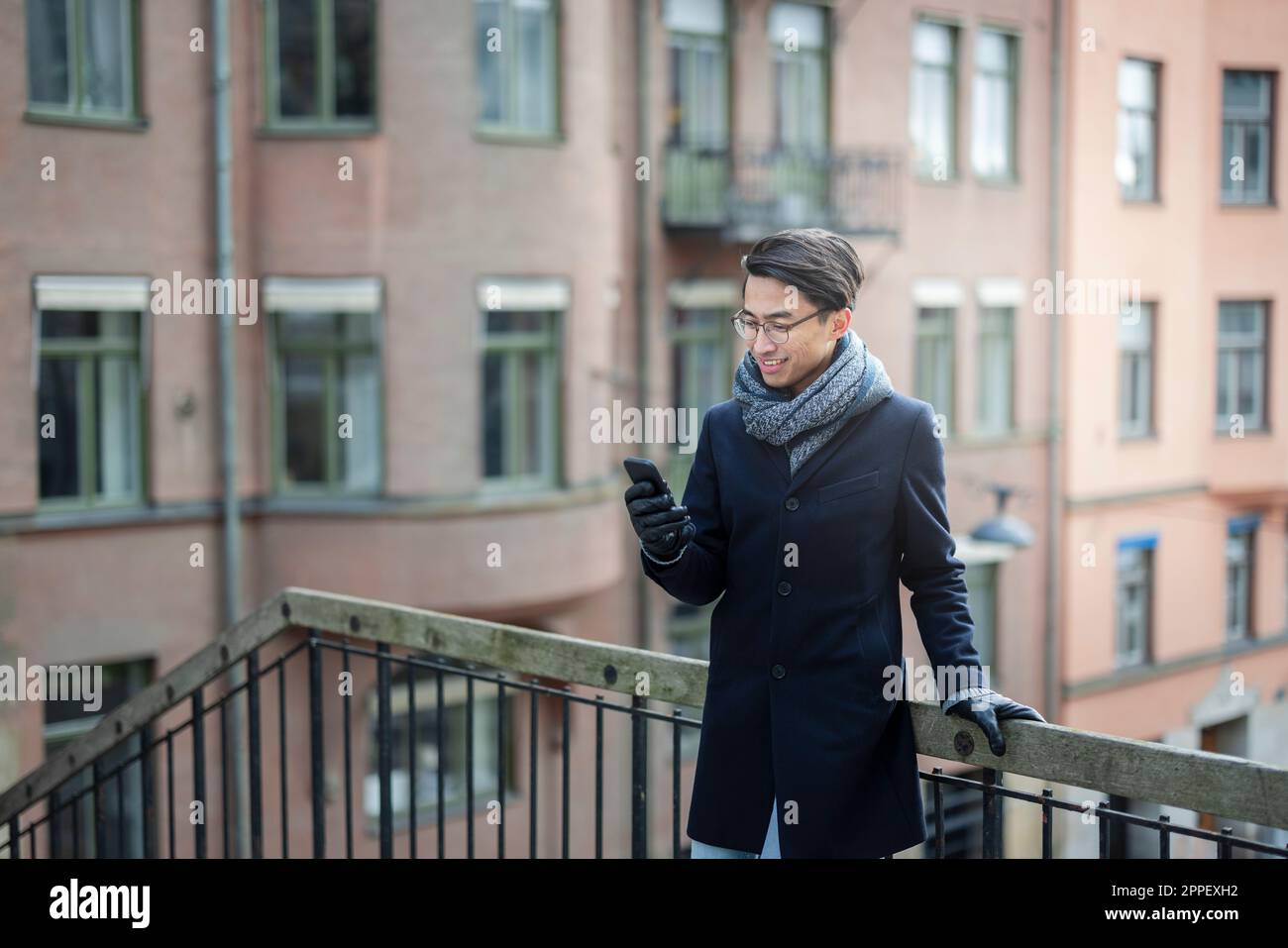 Handsome man with smartphone on footbridge Stock Photo