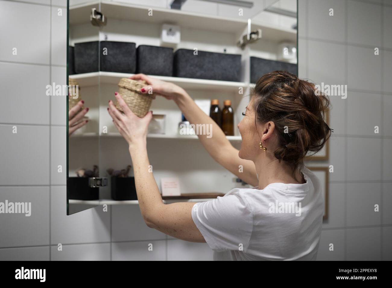 Woman putting basket in cupboard Stock Photo