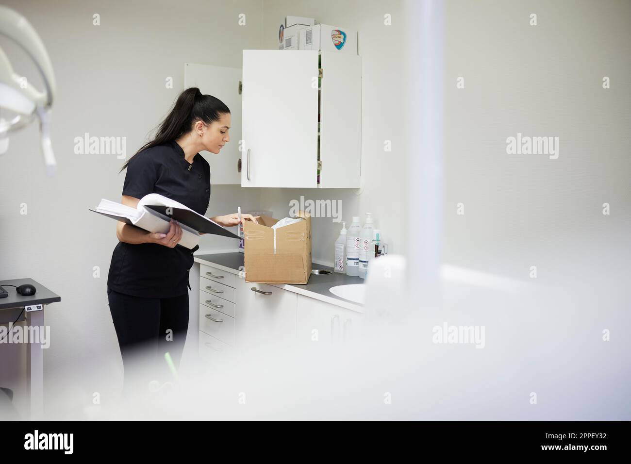 Female dentist in surgery putting supplies in cupboard Stock Photo Alamy